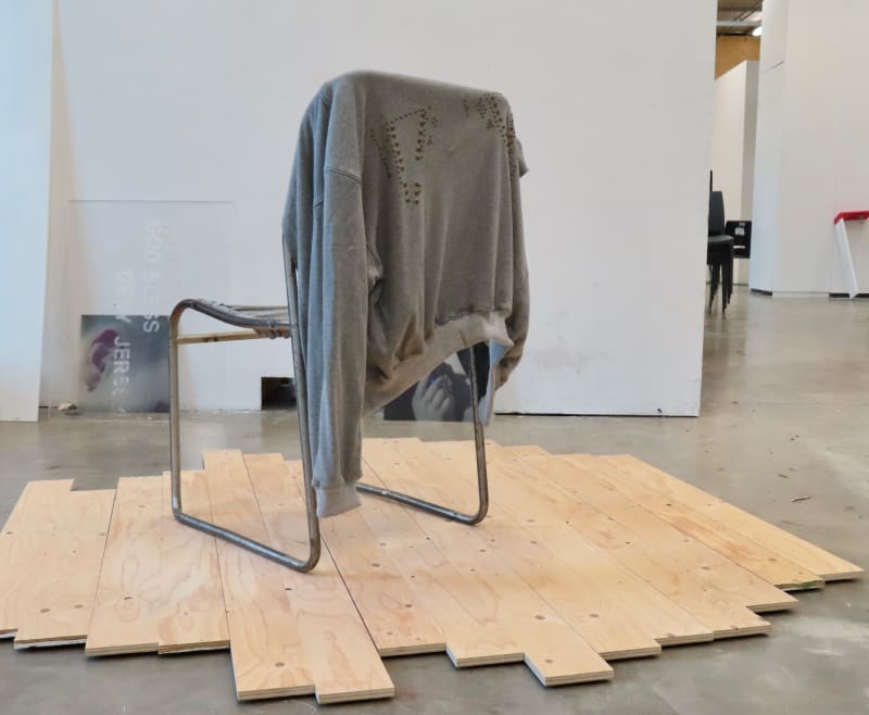 Grey jacket made of sweatshirt material rests on chair of same fabric.