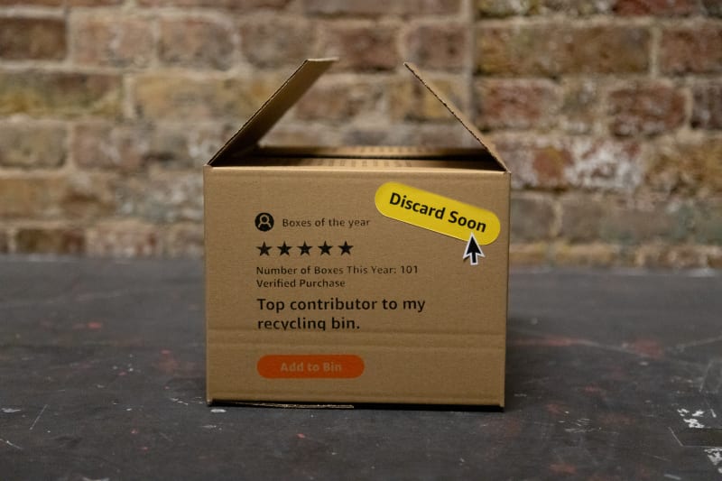 A close-up shot of the short side of box, with a rewritten Amazon review of the box and pasted with a custom die-cut sticker, saying Discard Soon