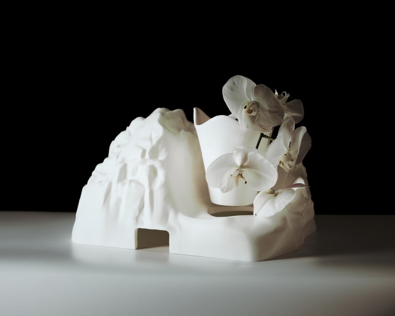 A white 3D-printed sculptural planter shaped like a mountain, with smooth, flowing textures resembling natural rock formations.