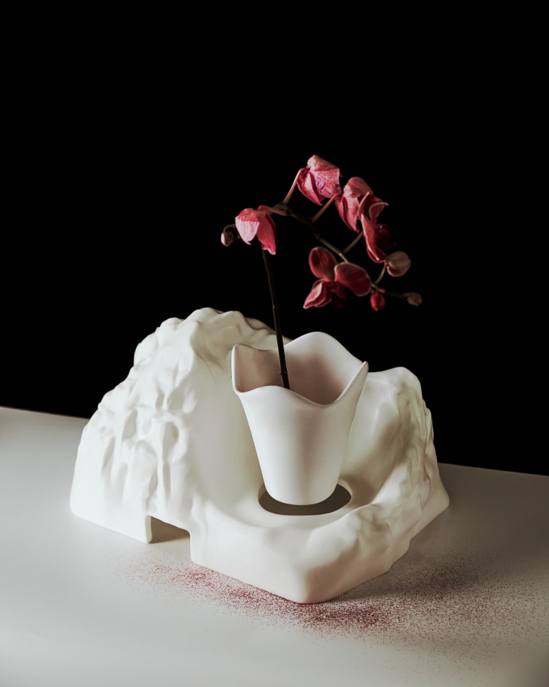 A white 3D-printed sculptural planter shaped like a mountain, with smooth, flowing textures resembling natural rock formations.