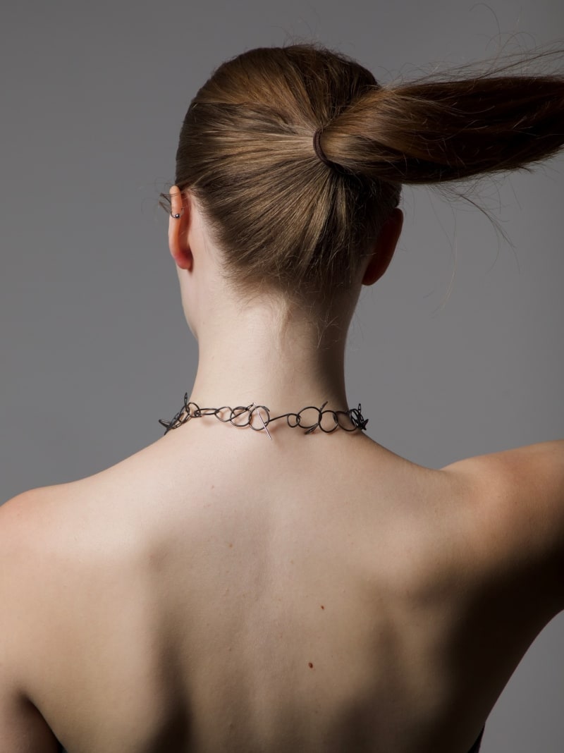 black necklace made out of sewing needles. form is jumbled and messy.