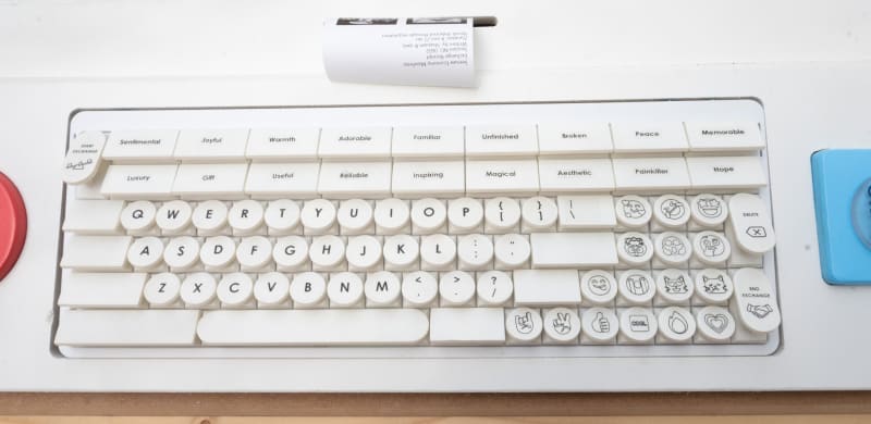 Below the seesaw is a retro-style white keyboard and a small thermal printer, which has printed a narrow receipt.