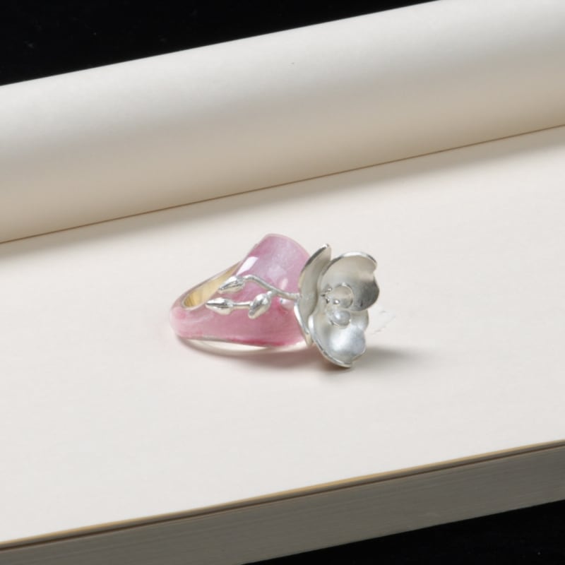 A rock crystal ring, the inner part of which is painted with fine mineral tourmaline pigment, creating a soft, glowing backdrop. Growing from the top 