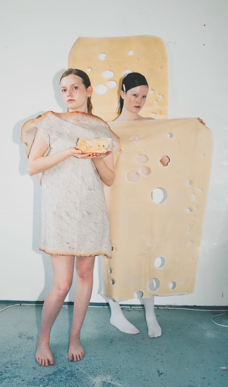 modeks wearing oversized cotton cheese and bread in a studio setting