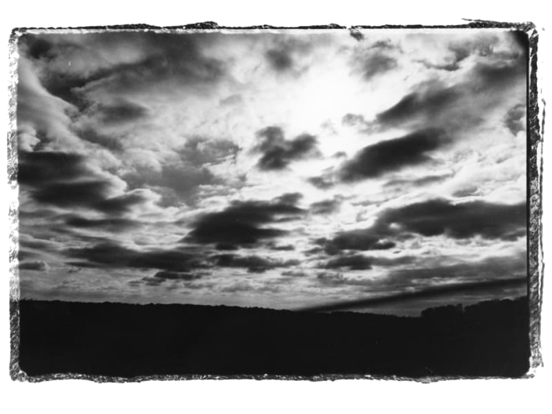 Black and white landscape image of sun shining through the clouds.
