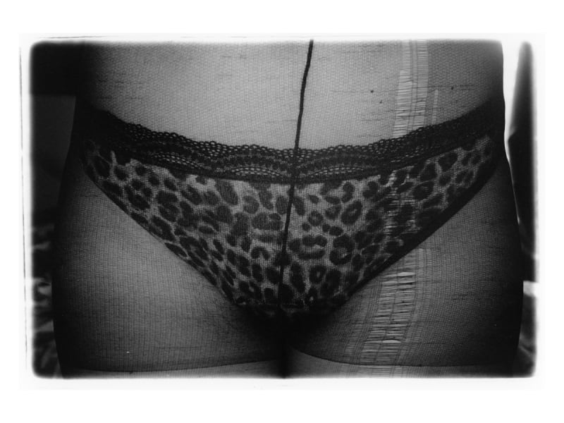 Black and white close-up image of leopard-print pants being worn underneath ripped tights. 