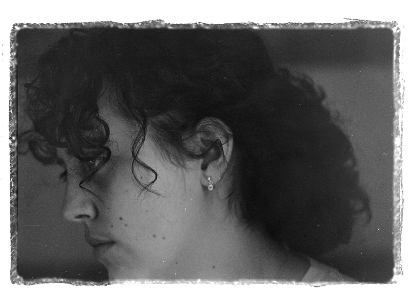 Black and white close up images of side profile of young woman. Focus drawn on the curls around her face.