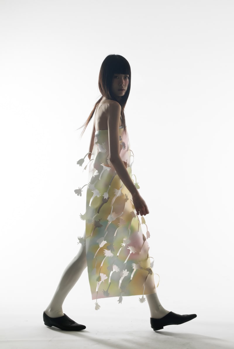 Model walking in pastel coloured laser cut polyster dress
