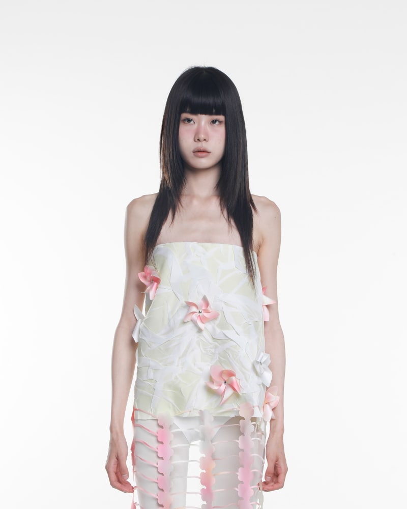 A woman wearing a crinkled yellow fabric with pink and white flower shaped pinwheels