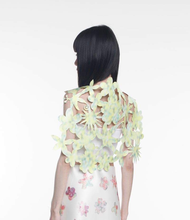 The back view of a woman wrapped in green and yellow floral-patterned fabric