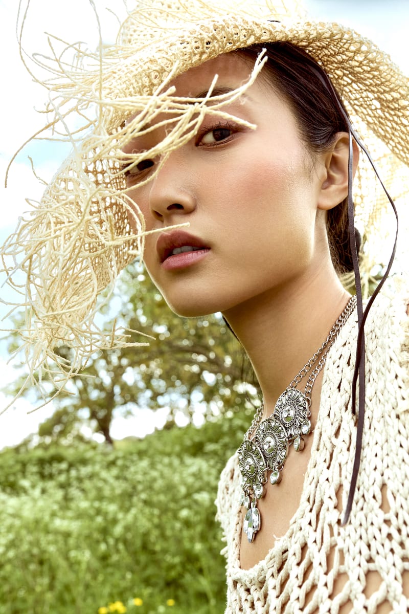 close up shot of asian female model wearing straw hat accessory from designer Miao paired with silver necklace.