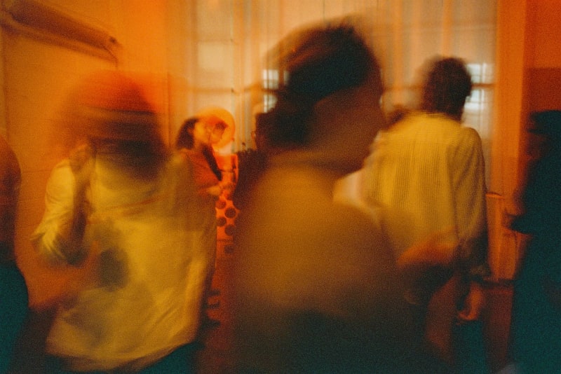 red/orange photograph of a group of people. motion blur