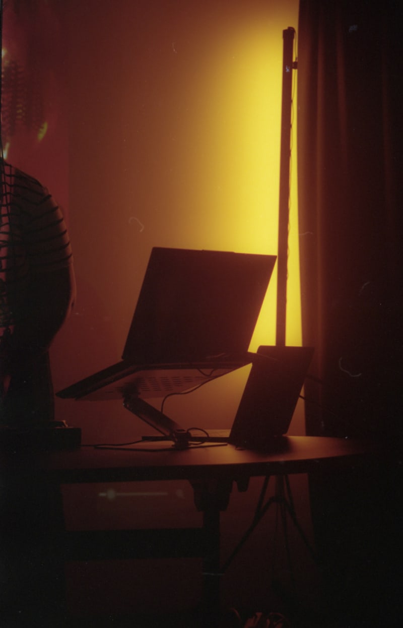 red/orange gradient photographs of a female person standing behind an elevated laptop.