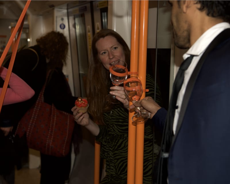 This is a pair of wine glasses that can be installed on the vertical poles in overground carriages, inviting strangers to clink glasses.