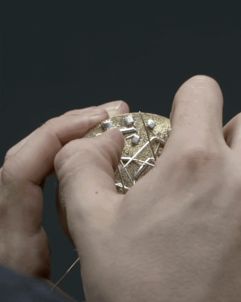 Initially, the gold concave shape reflects a distorted self-image, while the overlapping brooches represent confusion and uncertainty when trying to w