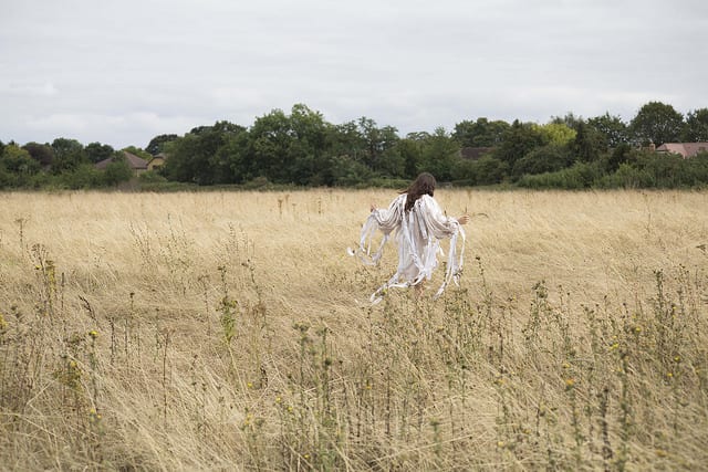 A woman in a white dress walking in a field.