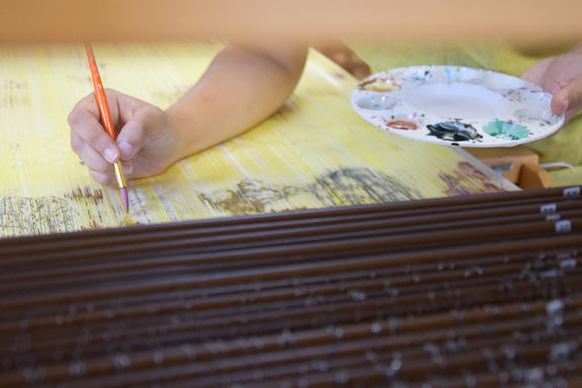 An image of the artist painting on fabric.