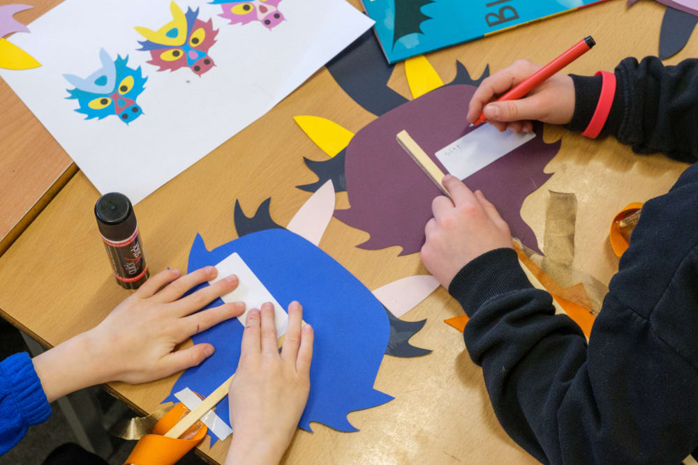 Children creating dragon masks with tape, glue and pens.