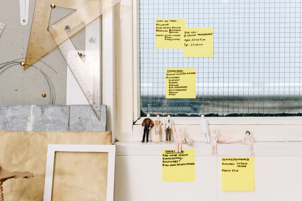 Close up shot of student's desk in a studio with post it notes and small model figurines