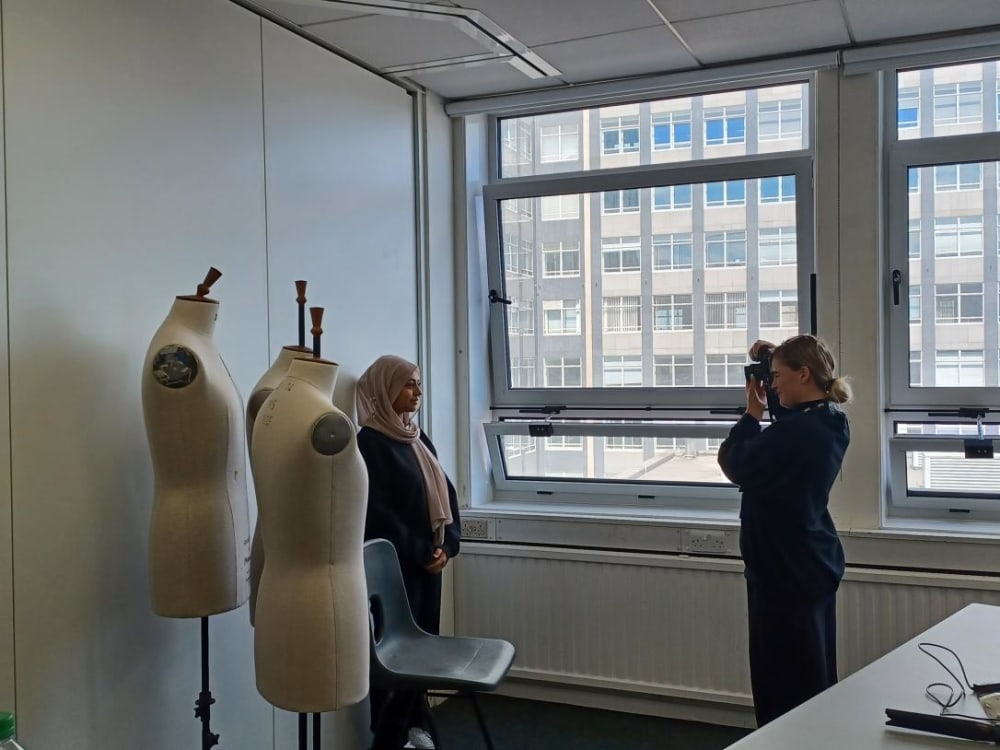 Student standing by mannequins having their photo taken