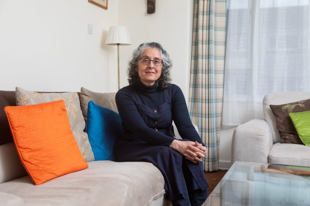 an older woman wearing glasses sitting on a sofa