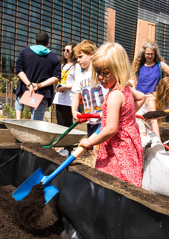 Girl digging sand with a workshop outside