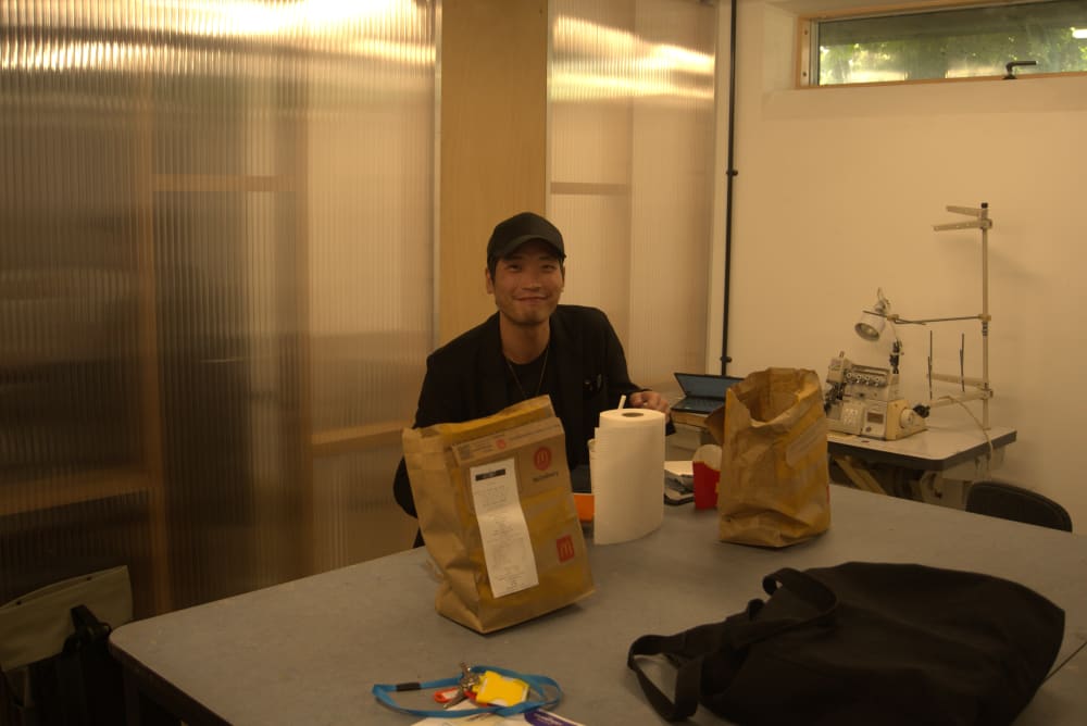 Man sat next to a table with food in a studio space.