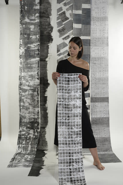 the female artist holding up her fabric prints. 