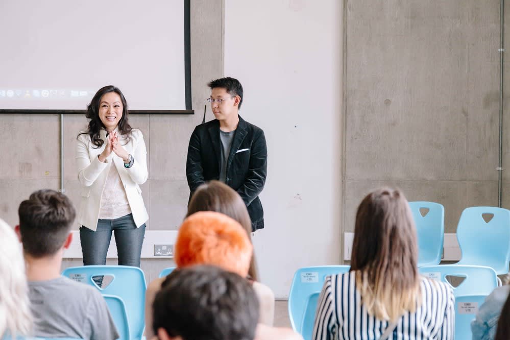 Man and woman standing talking at front of a seminar room