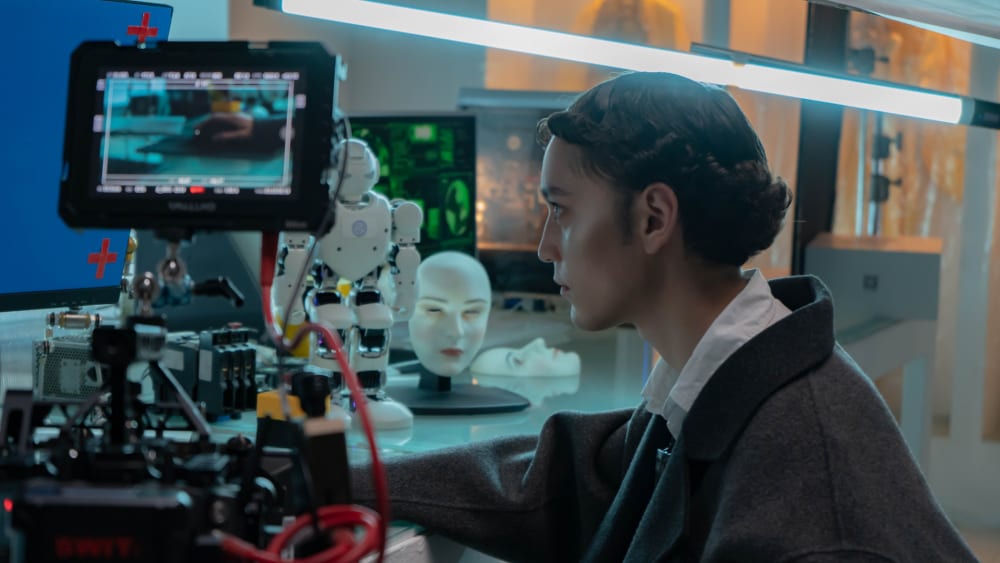 Behind the scenes of programmer looking at computer screen with camera shooting in frame