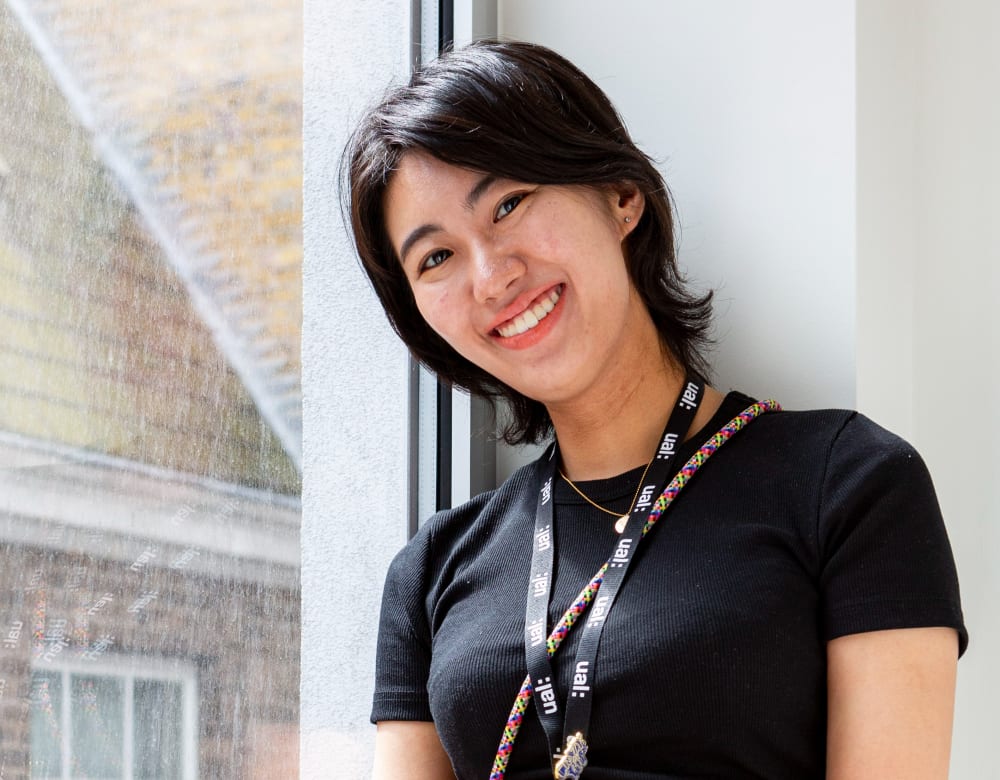 Student sitting in front of a window, smiling