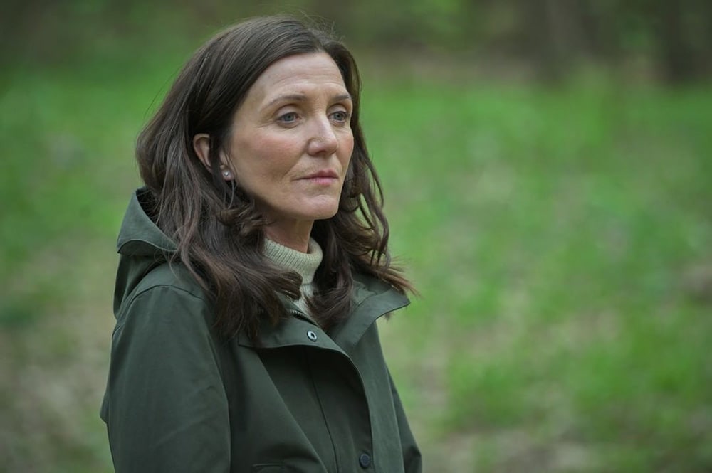 A still from Gangs of London where a woman stands in woodland.