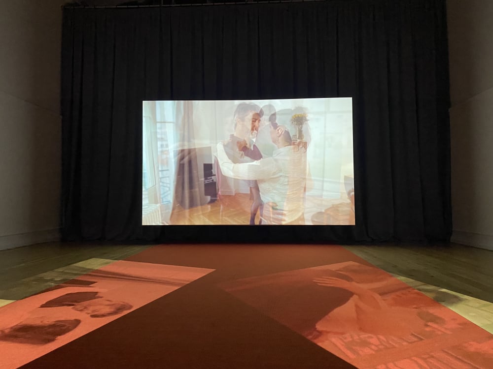 A large screen showing a film with reflections of the film on the floor