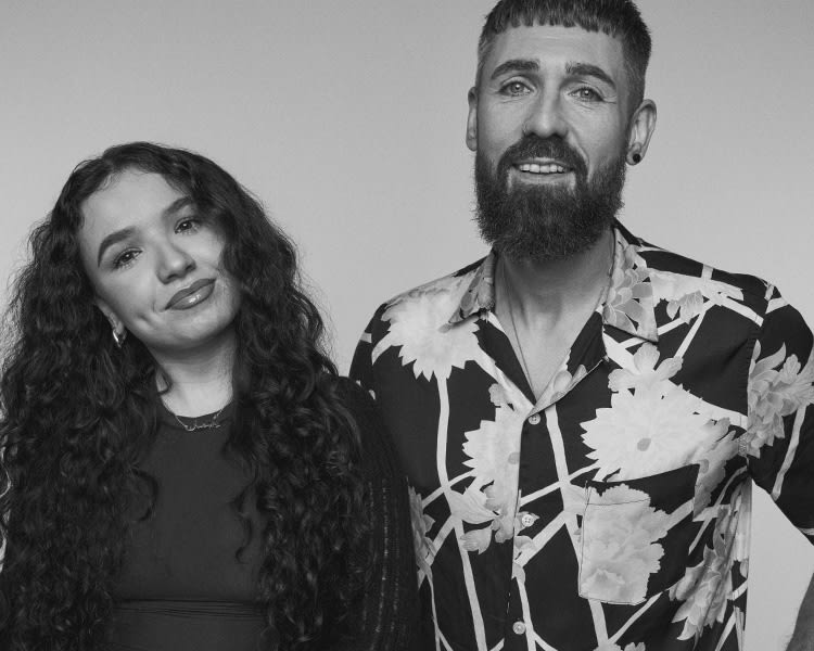 A Greyscale image of a man and a woman standing and smiling at the camera