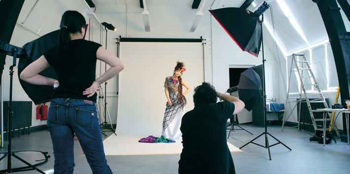 Photography studio with female model in a dress and two photographers