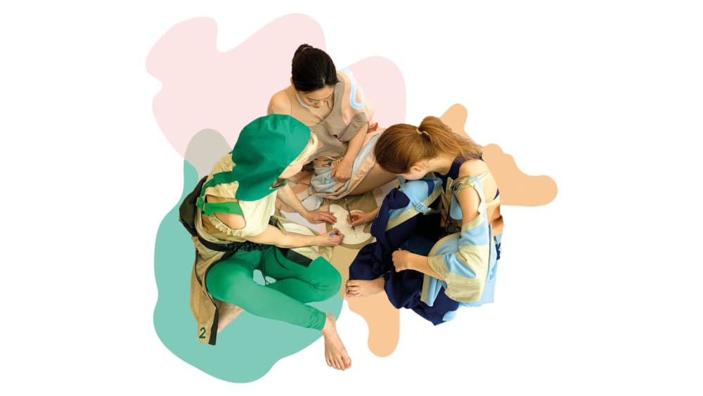 graphic of three people in multicoloured garments sitting cross-legged on top of pink, green and orange splotches of colour