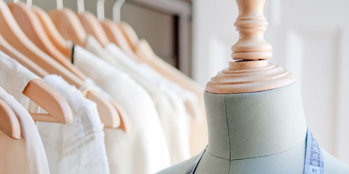 A mannequin in front of a rail of clothes.