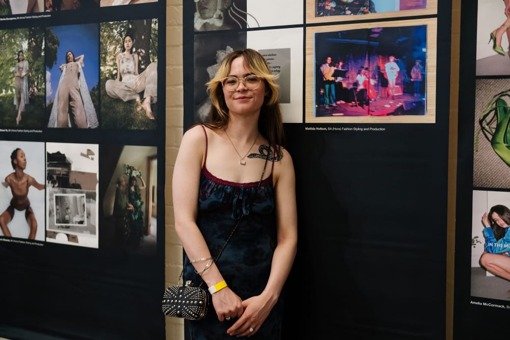 Student posing in front of work of panelled images
