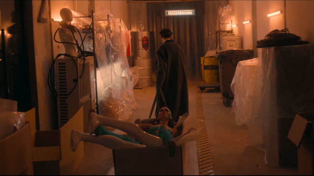 Programmer pulling Tenet the cyborg in a cardboard box using a flat trolley device