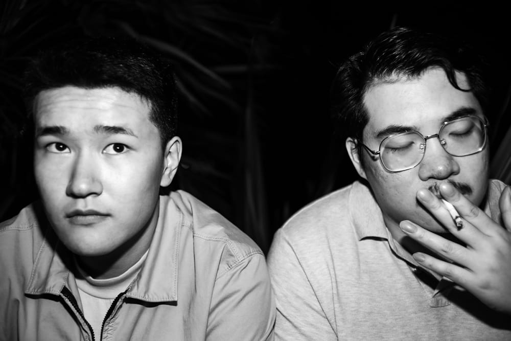 Photograph of two people smoking cigarettes.