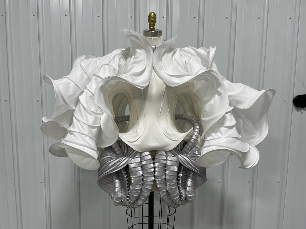 A white silk corset with elaborate, sculptured, symmetrical sleeves and a silver curved skirt.  