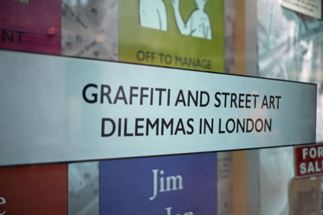 A shot of a window panel with colourful illustrated and text panels and a centre text panel with the wording Graffiti and Street Art Dilemmas in London