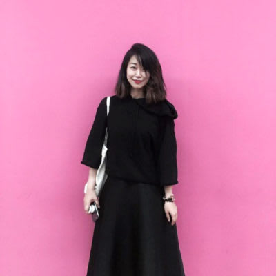 Woman wearing all-black in front of a pink wall