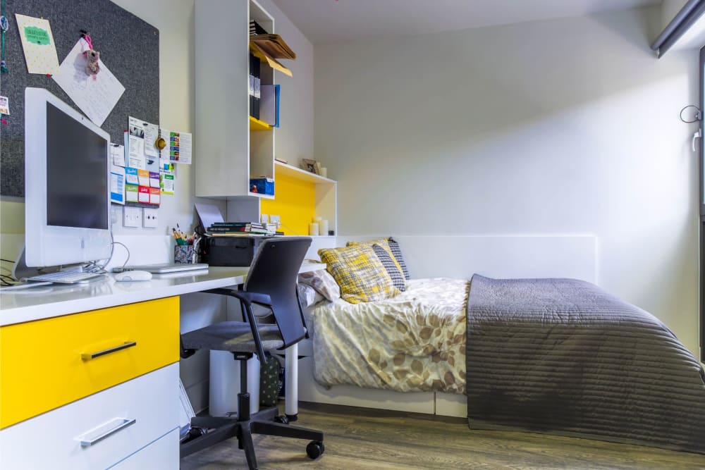 Photo of a Studio (mobility adaptable) room at Highline Building, showing a double bed, large desk with swivel chair, built in drawers.