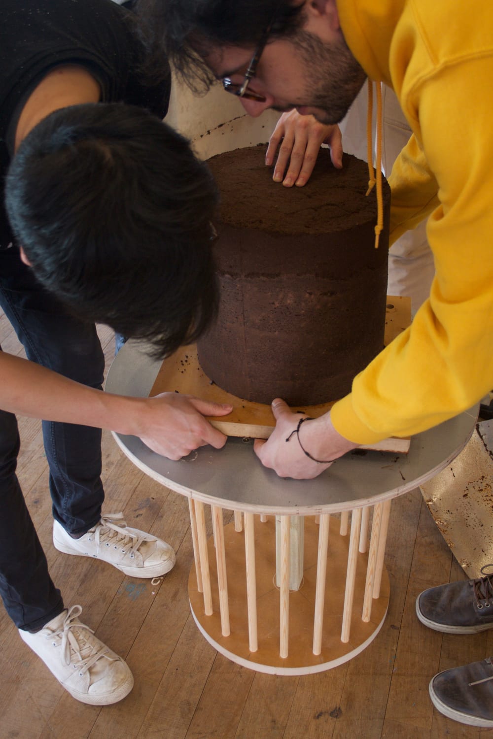 Two project participants, sculpting the coffee granules into a Cylinder shape and placing on a podium in the Tate Modern 