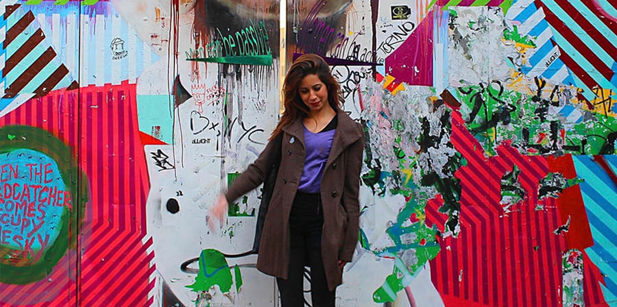 Photo of Su against a graffitied wall