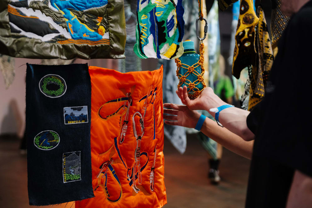 Hands touching garments hanging in exhibition