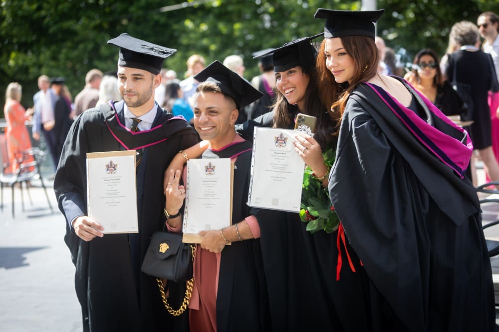 Graduates celebrating and posing for photos at their graduation ceremony.