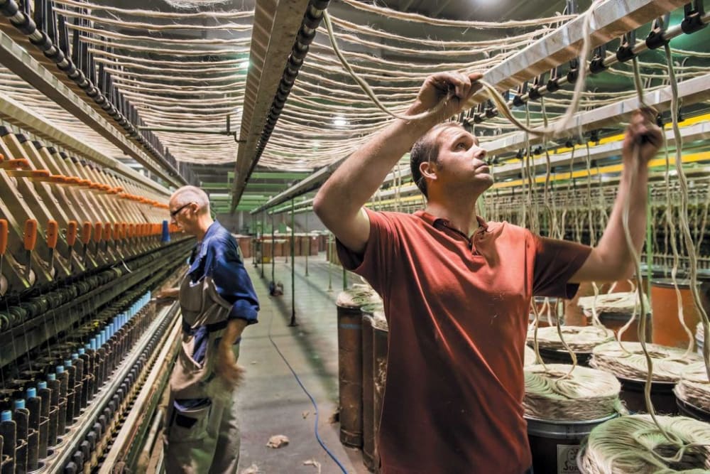 Two men working with linen in a factory