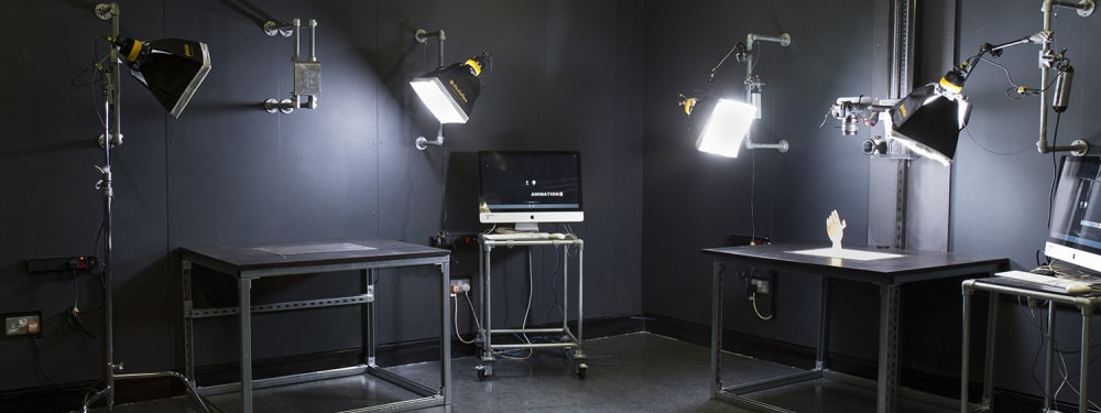 A dark room with an iMac and lighting 